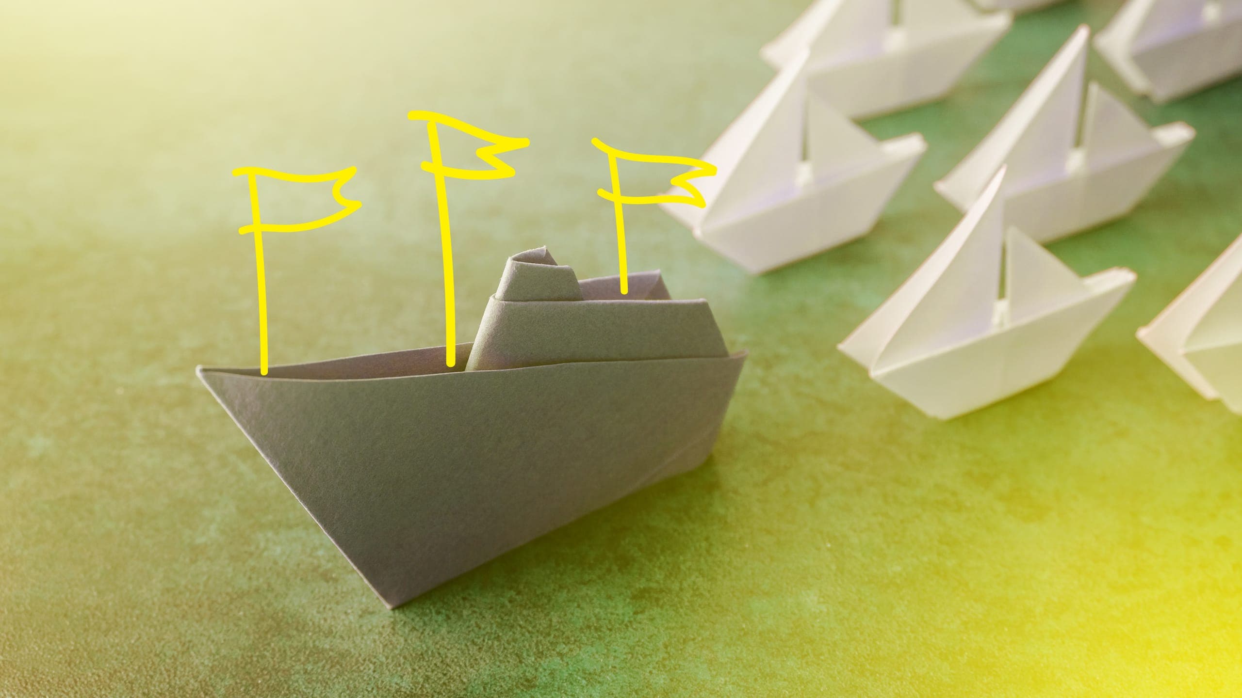An origami ship with flags illustrated on it, leading other ships.
