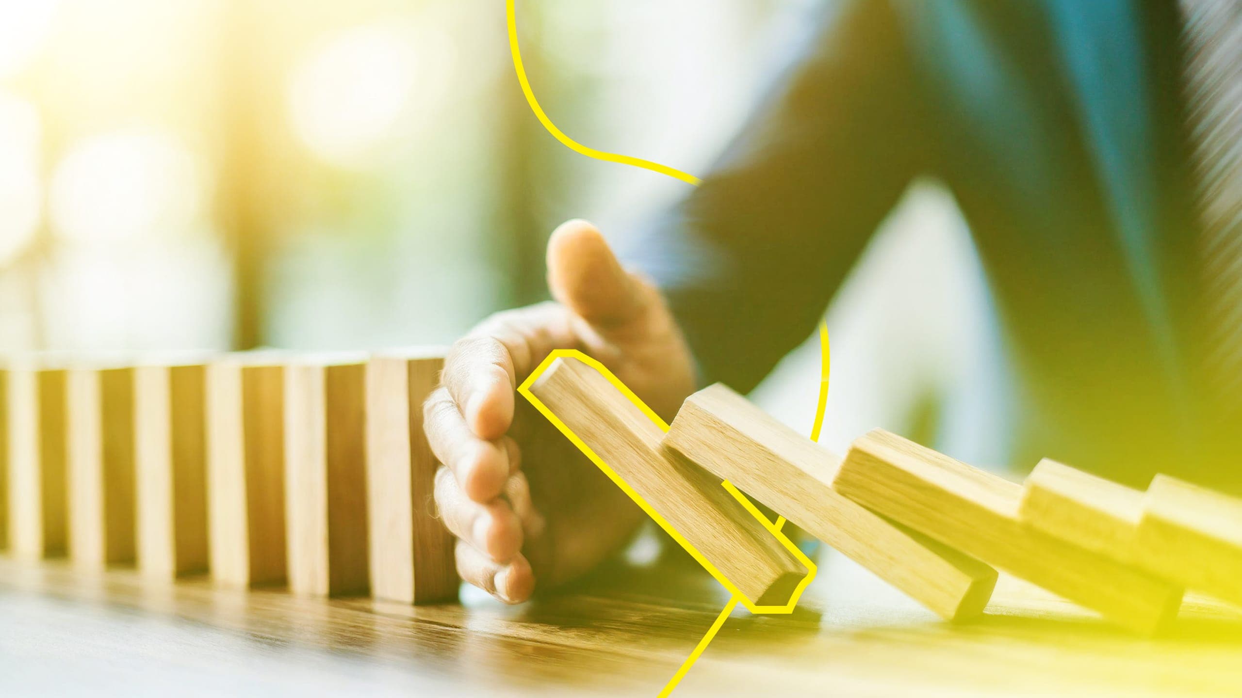 A hand stopping a series of dominos from falling