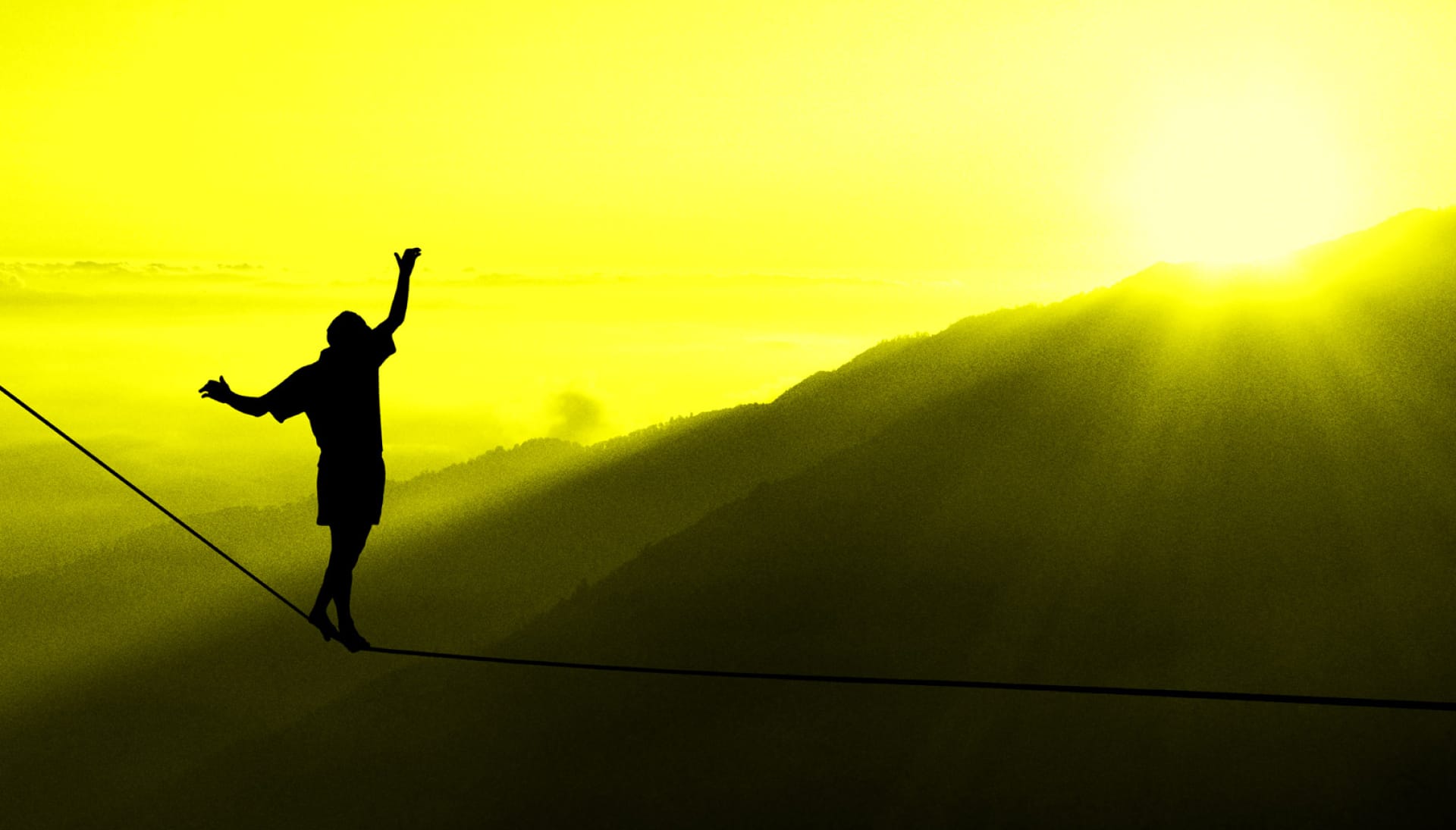 A person walking a tightrope as the sun sets